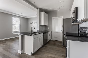 an empty kitchen with white cabinets and black counter tops at Alexandria of Carmel Apartments, Carmel, Indiana